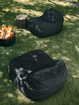 Two gray outdoor lounge chairs on a grassy lawn with one chair partially covering a fire pit.